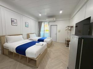 a hotel room with two beds and a flat screen tv at The Sceneสุพรรณบุรี in Suphan Buri