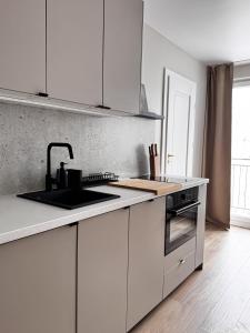 a white kitchen with a sink and a stove at Apartament Cicha Przystań w centrum Zakopanego APARTZAKOP in Zakopane