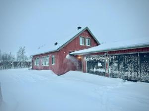 un fienile rosso con neve per terra di Rensjön Guesthouse a Herräng
