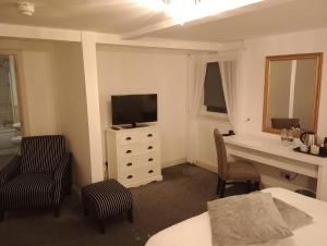 a hotel room with a desk and a television and a bedroom at Whiston Hall in Whiston