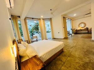 a bedroom with a large bed in a room with windows at OLA Tangalle in Tangalle