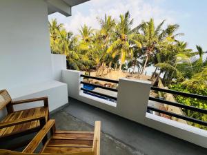 a balcony with a view of the beach and palm trees at OLA Tangalle in Tangalle