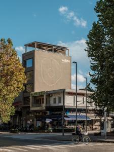 Kaoma Comfort Suites في تريكالا: شخص يركب دراجة أمام المبنى