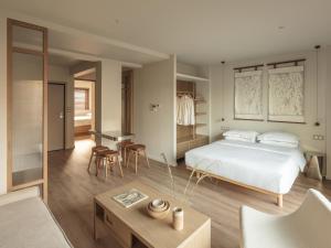 Kaoma Comfort Suites في تريكالا: غرفة نوم بها سرير وطاولة وكراسي