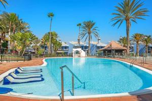 a large swimming pool with palm trees in a resort at Casa Tabera - Sun Club Playa del Águila in Playa del Aguila