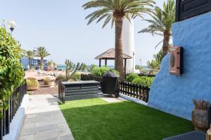 a yard with grass and a blue fence and palm trees at Casa Tabera - Sun Club Playa del Águila in Playa del Aguila