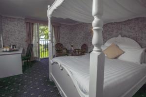 a bedroom with a white bed with a canopy at Normanton Park Hotel, BW Signature Collection in Oakham