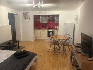 a living room with a table and a kitchen at Cozy 1 Bedroom Basement Flat in London