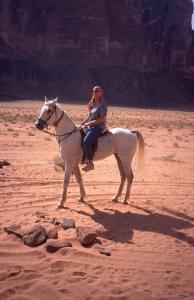 a woman riding a white horse in the desert at Rum Awaad luxury camp in Wadi Rum