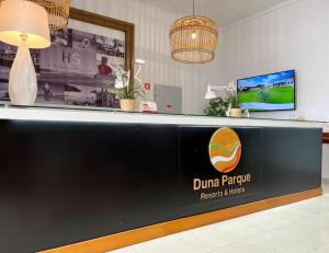 a reception desk with a dunder papride sign on it at Vicentina Rooms - Duna Parque Group in Vila Nova de Milfontes