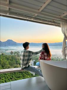 Ban SakoenにあるPhulangcarの景色を眺めながら窓辺に座っている男性と女性
