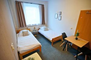a room with two beds and a desk and a window at die GastHütte in Eisenhüttenstadt