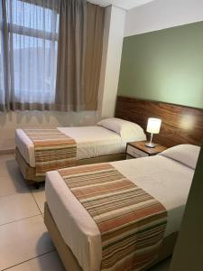 una camera d'albergo con due letti e una finestra di Hotel Flat Itaipava a Itaipava
