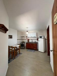 a kitchen with a table and a white refrigerator at Apartamentos da Jo in Camanducaia