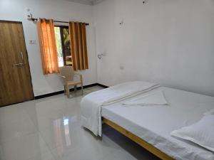 een slaapkamer met een bed, een stoel en een raam bij Coastal Konkan in Malvan