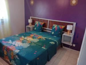 a bedroom with a bed with a purple wall at gîte La Cannaie in Port-Louis