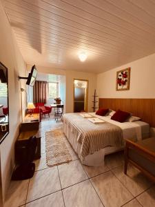 a bedroom with a bed and a living room at Hospedaria Vila Rica - Pousada a 1 km do Centro Histórico in Ouro Preto