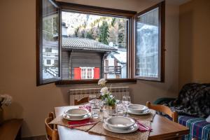 VivimiHome - Rifugio Genzianella في سان دومينيكو: طاولة عليها صحون واكواب مع نافذة