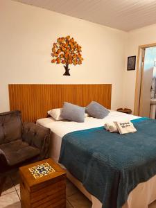 a hotel room with two beds and a chair at Hospedaria Vila Rica - Pousada a 1 km do Centro Histórico in Ouro Preto