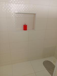 a red candle sitting on a shelf in a shower at Casa proximo ao aeroporto in Florianópolis