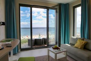 a living room with a large window with a view of the beach at SEETELHOTEL Kaiserstrand Beachhotel in Bansin