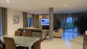 ein Wohnzimmer mit einer Couch und einem Tisch und einem Fernseher in der Unterkunft Villa 300m2 piscine chauffée et jacuzzi-spa de nage in 