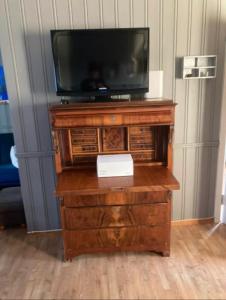 un centro de entretenimiento de madera con TV en la parte superior en Leilighet i Damstien, 