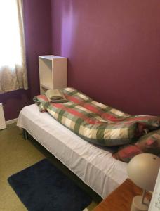 Un dormitorio con una cama y una pared morada. en Leilighet i Damstien, 