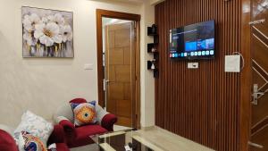 a living room with a red chair and a flat screen tv at Infinium Stay in Rishīkesh
