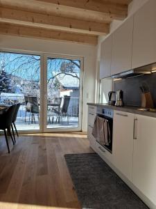 Cute House with terrace and garden في إنسبروك: مطبخ مع دواليب بيضاء وغرفة طعام مع طاولة