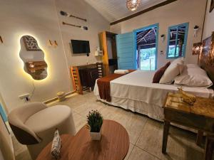 a bedroom with a bed and a chair and a table at Pousada de Charme Emirados in Ilhabela