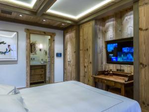 a bedroom with a bed and a tv and a sink at Chalet raffiné avec chambres luxueuses et services inclus - FR-1-564-62 in Courchevel