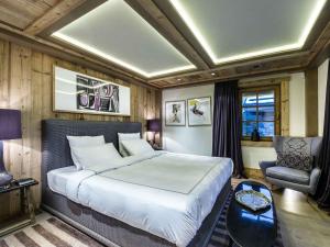 a bedroom with a large bed and a chair at Chalet raffiné avec chambres luxueuses et services inclus - FR-1-564-62 in Courchevel