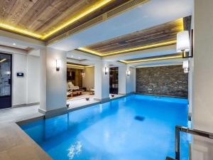 a large swimming pool in a room with a brick wall at Chalet raffiné avec chambres luxueuses et services inclus - FR-1-564-62 in Courchevel