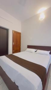 a large white bed in a room with a wooden door at TAMARA VISTA Executive Homestay in Varkala