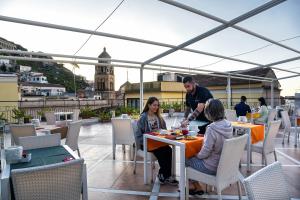 a man and two women sitting at a table on a roof at Amalfi Suite Boutique Hotel in Amalfi