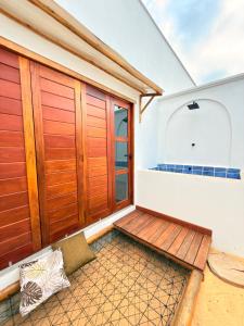 een balkon met houten deuren en een bank bij CACTUS CLUB - Hotel, Wellness Center & Spa in São Miguel do Gostoso