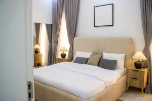 Un dormitorio con una gran cama blanca con dos lámparas. en B'gatti Apartments, en Lagos 30 fotos más