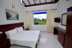 una camera da letto con un letto bianco e una finestra di Blue Villa Wadduwa a Wadduwa