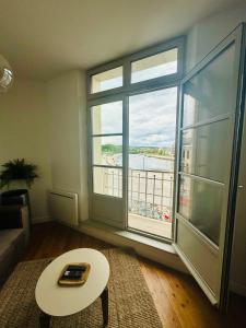 Una sala de estar con una mesa y una gran ventana. en Côté Aisne - vue imprenable, en Soissons