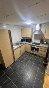a kitchen with wooden cabinets and a stove top oven at Cosy & Modern 2 Bedroom Apartment in Cardiff