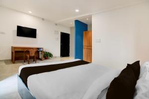 Un dormitorio con una cama y un escritorio con televisión. en Super Hotel O Avigna Premium, en Bhubaneshwar