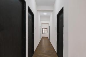a hallway with black doors and a wooden floor at Hotel O Infocity Square Road Bhubaneswar Formerly Avigna Premium in Bhubaneshwar