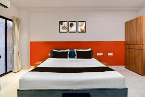 Un dormitorio con una cama grande con una pared naranja. en Super Hotel O Avigna Premium, en Bhubaneshwar