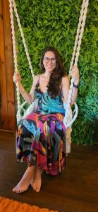 a woman is sitting on a swing at Pousada de Charme Emirados in Ilhabela +157 photos