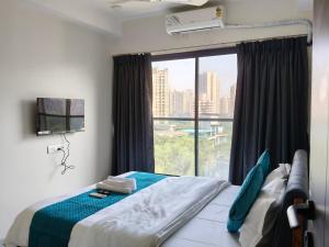 Un dormitorio con una cama y una ventana grande. en UrbanNest Service Apartments Powai, en Bombay