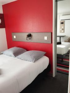 ein Schlafzimmer mit einem roten Kopfteil und einem Bett in der Unterkunft Kyriad Direct Saintes in Saintes