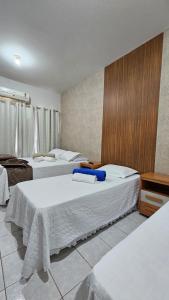 Una habitación de hotel con dos camas con sábanas blancas. en Hotel Familiar, en Salinas