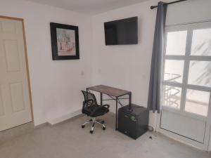 una stanza con una scrivania, una sedia e una televisione di Mini Hotel El Mezquite a Villa Doctor Mora