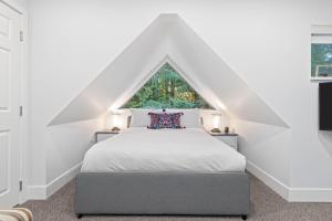 a bedroom with a white bed with a window at Modern Home with Forested Views by Harmony Whistler in Whistler